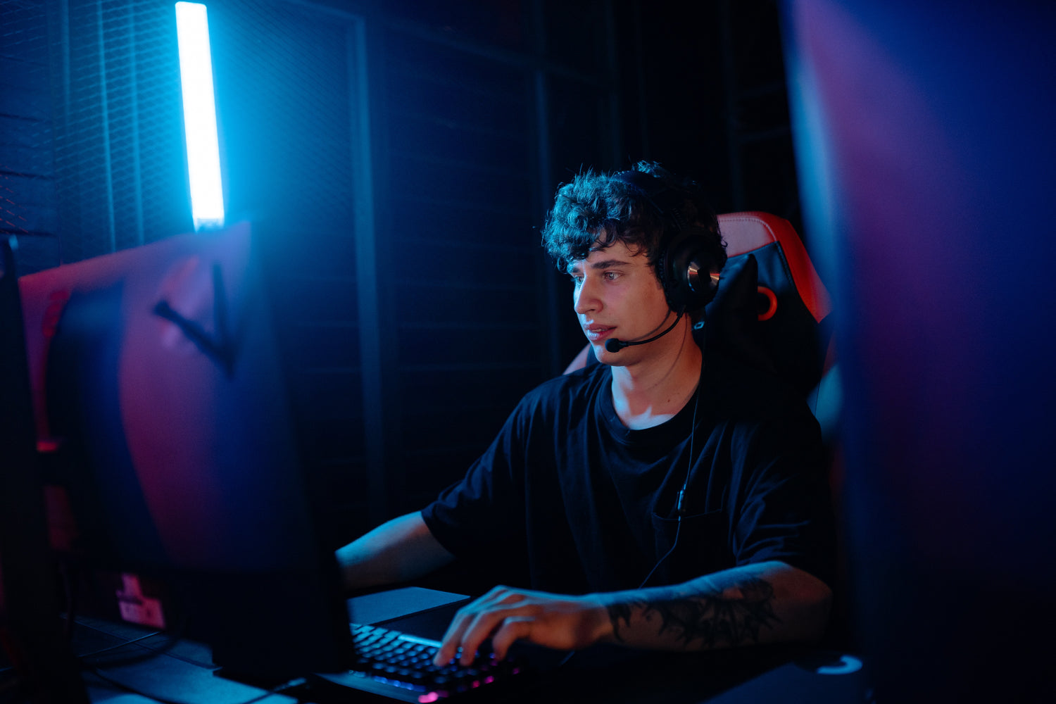 Young man with headphones gaming on a computer in a dark room